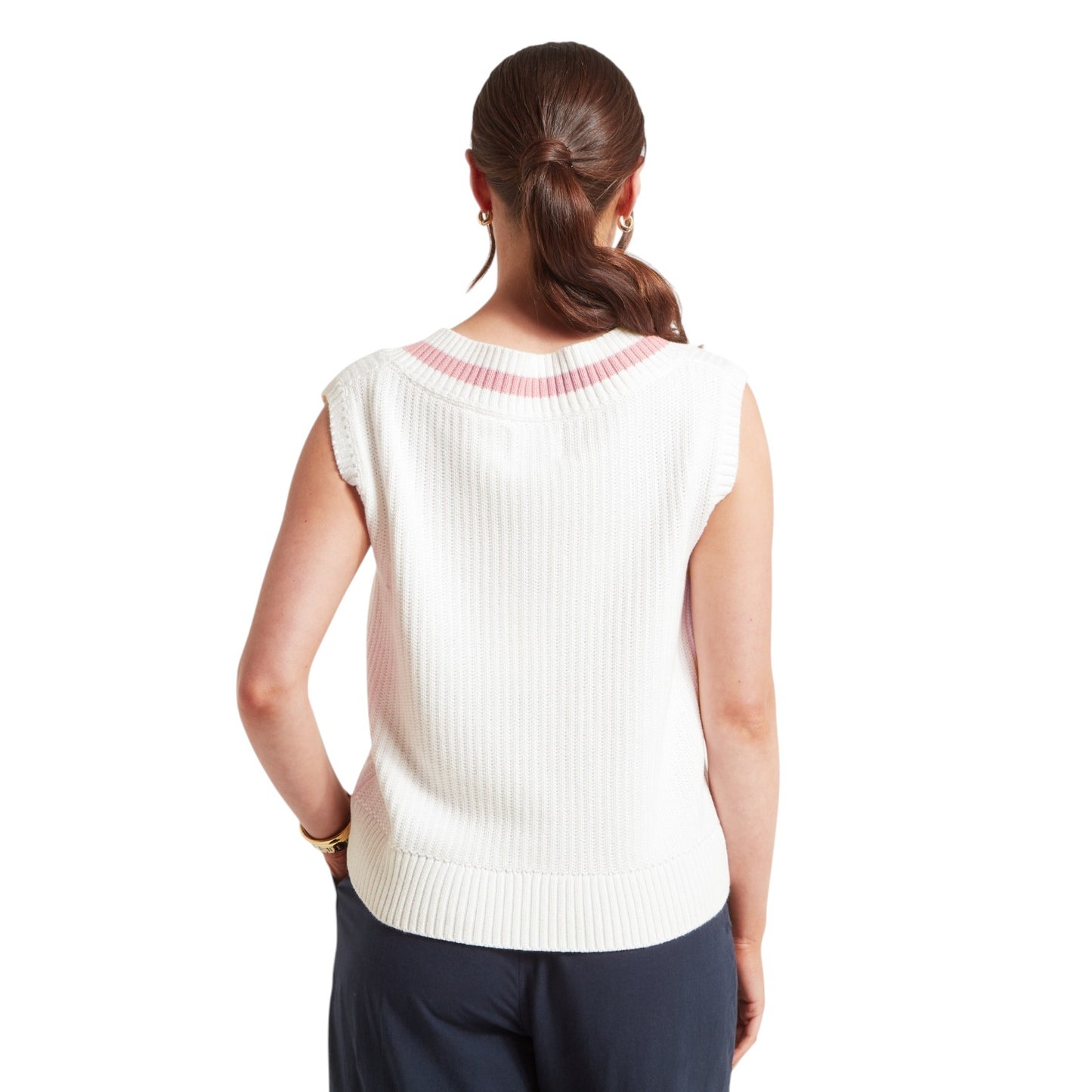 Woman wearing a white sleeveless top with a subtle pattern on the back, standing against a plain background.