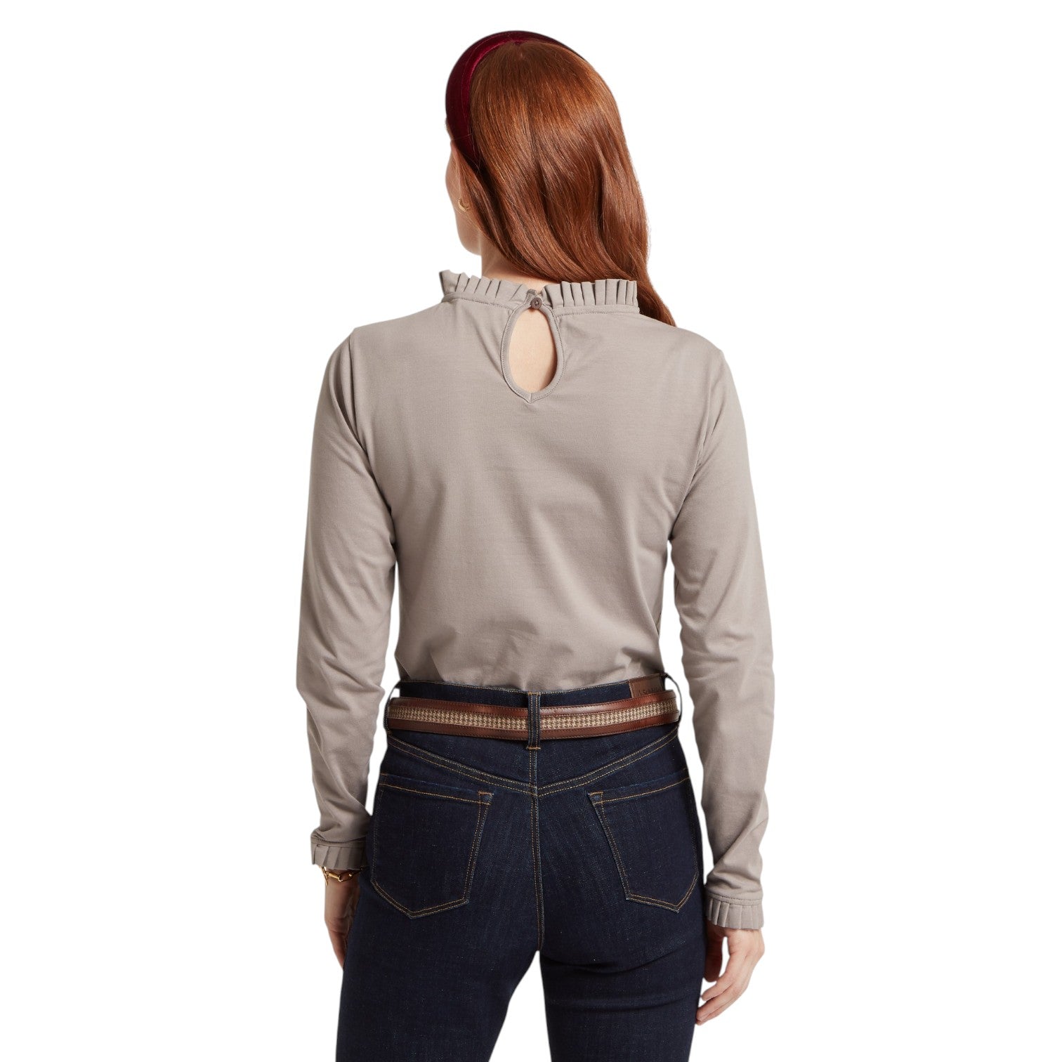 Person wearing a beige long-sleeve shirt with a cutout design on the back, standing against a white background.