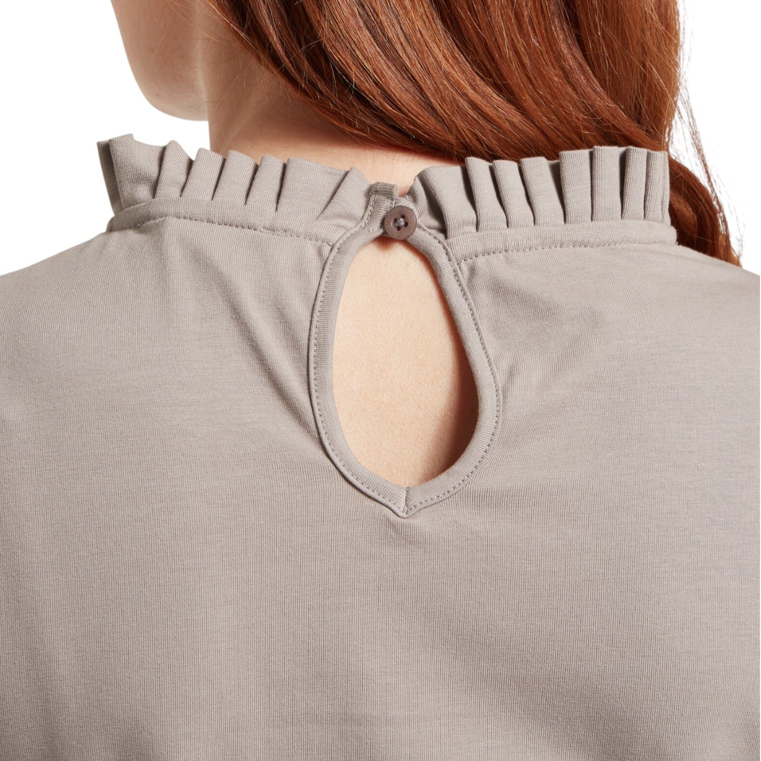 Close-up of a beige garment with a unique neckline design on a white background