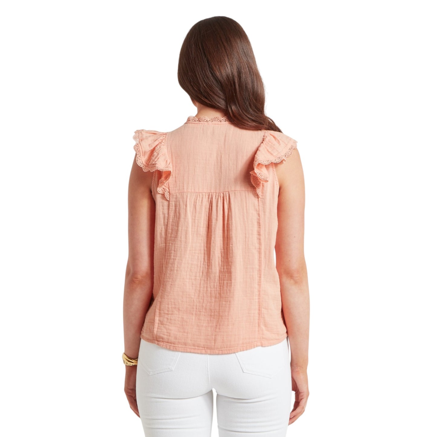 Woman wearing a peach-colored blouse with ruffled shoulders on a white background