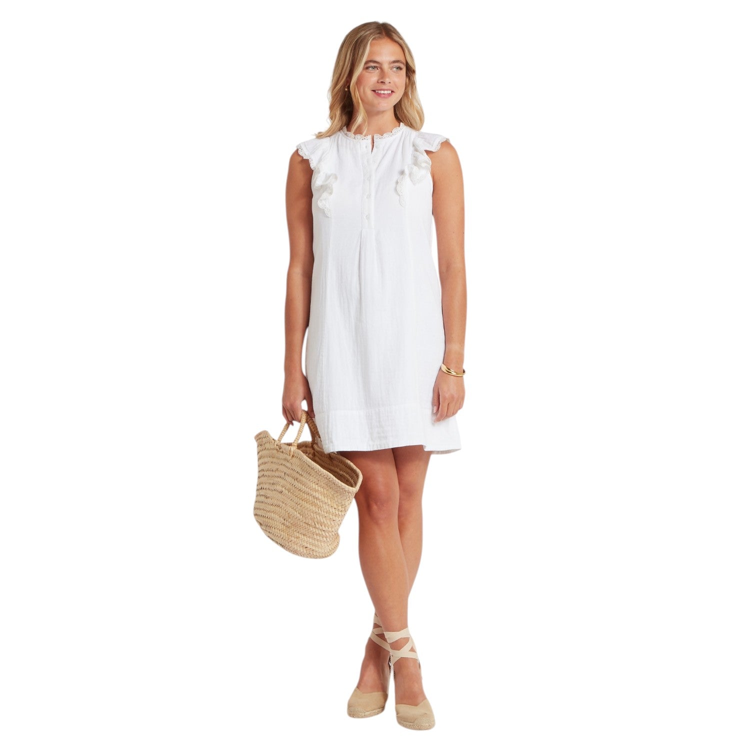 Woman wearing a white dress holding a straw bag on a white background