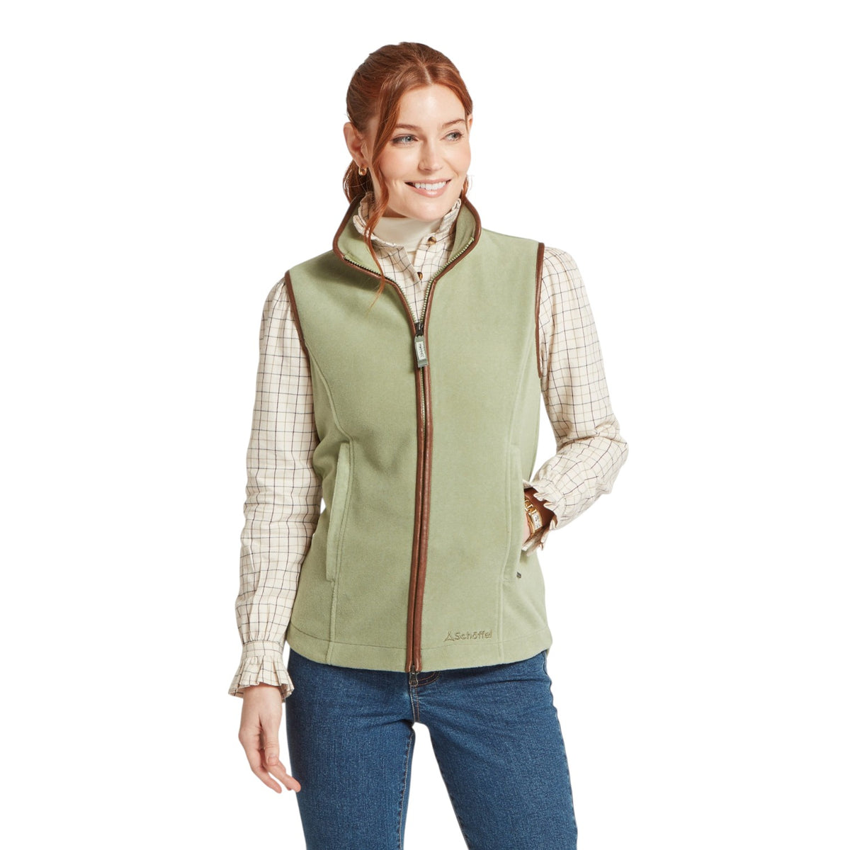 Woman wearing a green vest over a plaid shirt on a white background