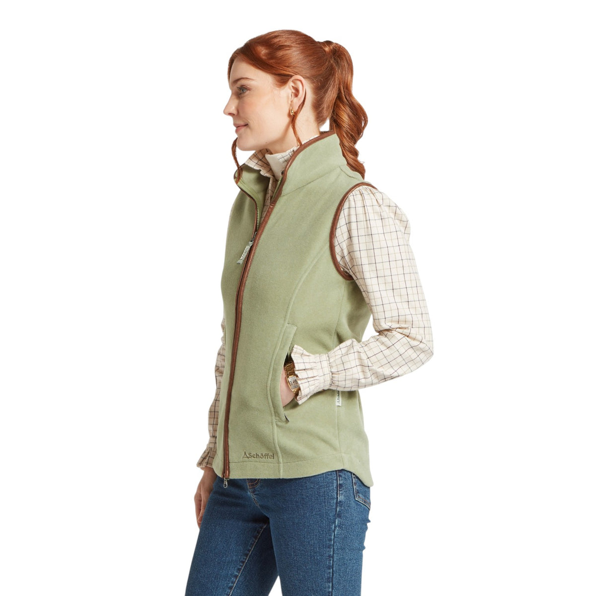 Woman wearing a green vest over a plaid shirt on a white background