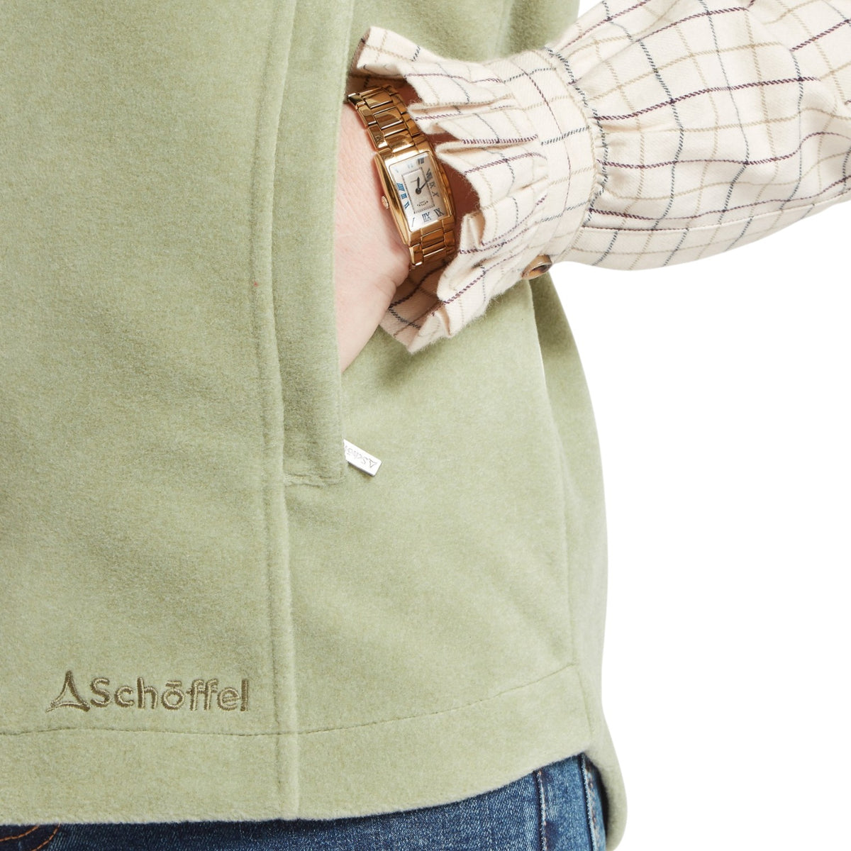 Person wearing a green jacket with 'Aschoffel' branding, holding a watch.