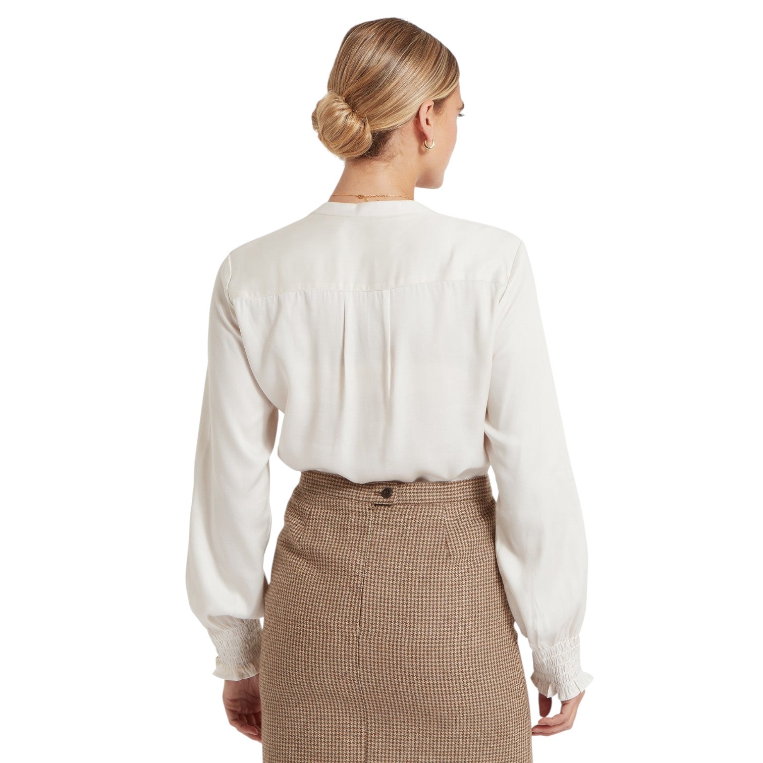Woman wearing a white blouse and brown checkered skirt on a white background