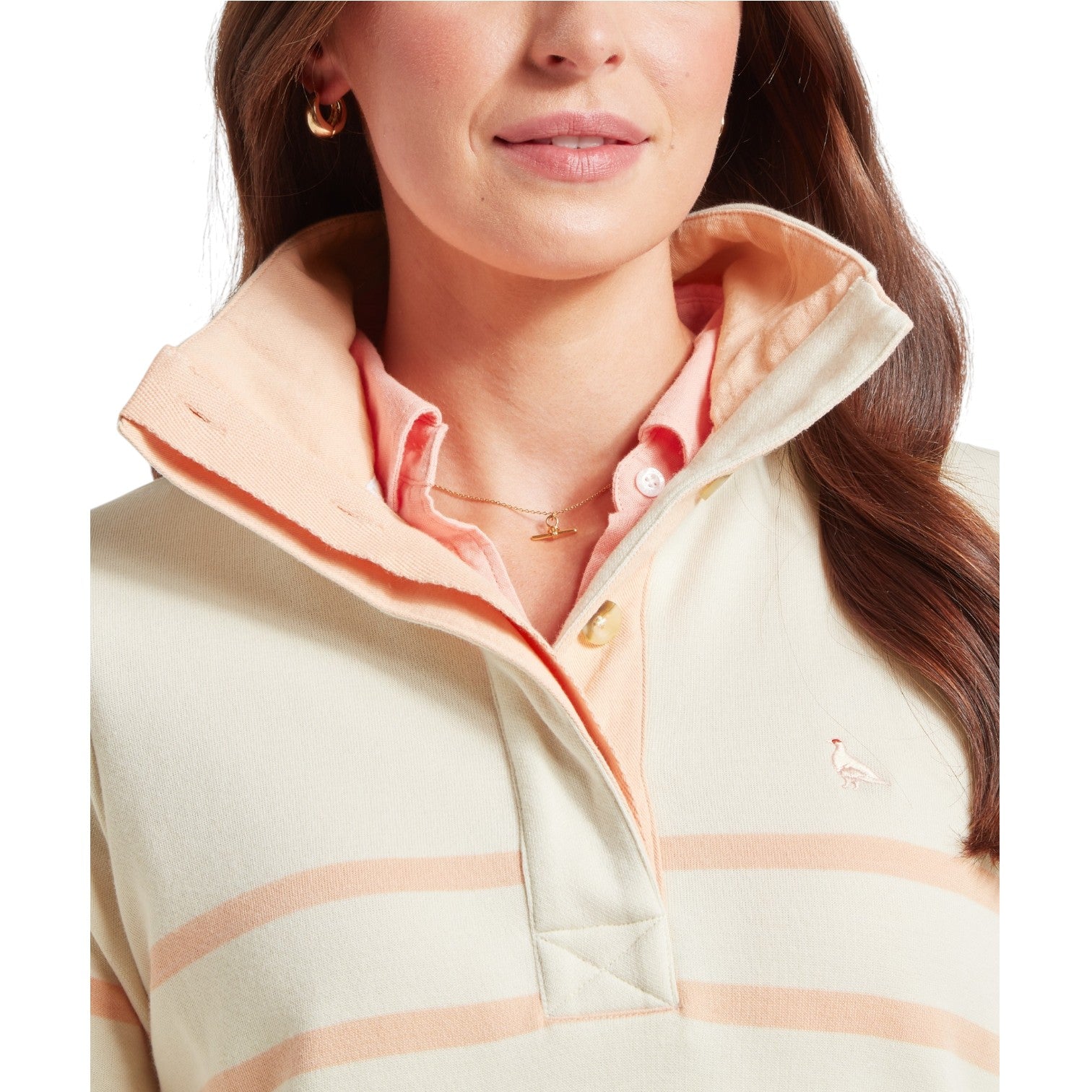 Woman wearing a light-colored jacket with a pink collar and plaid pattern.