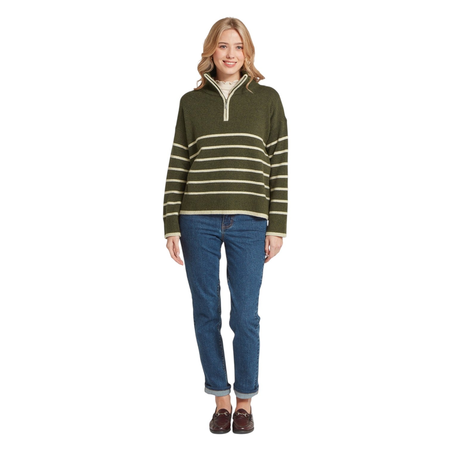 Woman wearing a green and white striped sweater with blue jeans on a white background