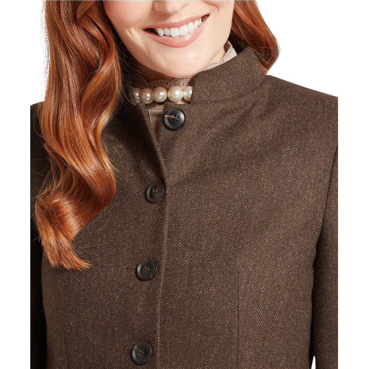 Close-up of a brown coat with buttons and a pearl necklace worn by a person with red hair.