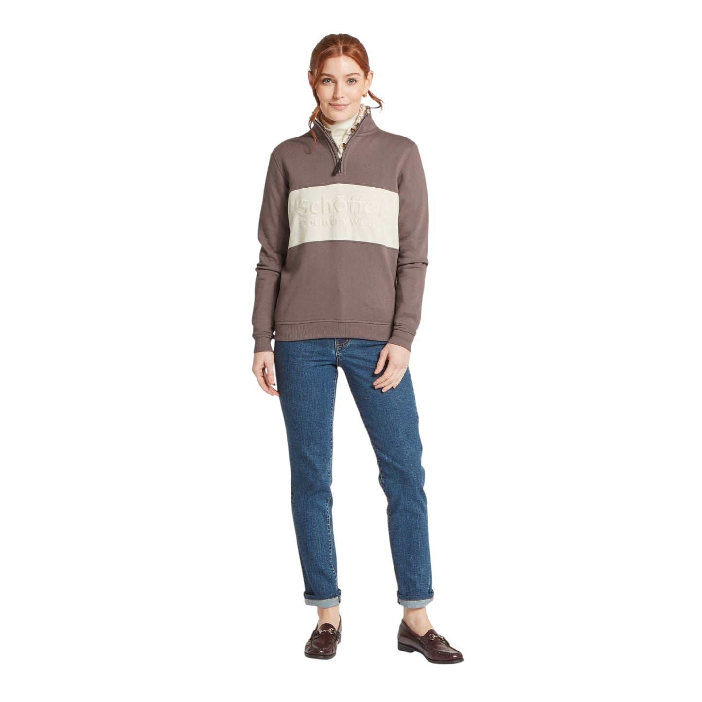 Woman wearing a brown and beige striped sweater with blue jeans on a white background