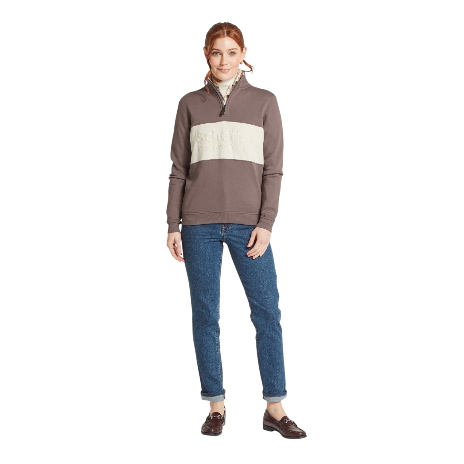 Woman wearing a brown and beige striped sweater with blue jeans on a white background