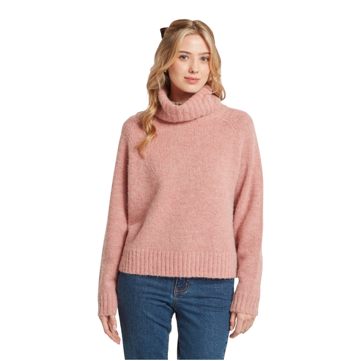 Woman wearing a pink turtleneck sweater and blue jeans on a white background