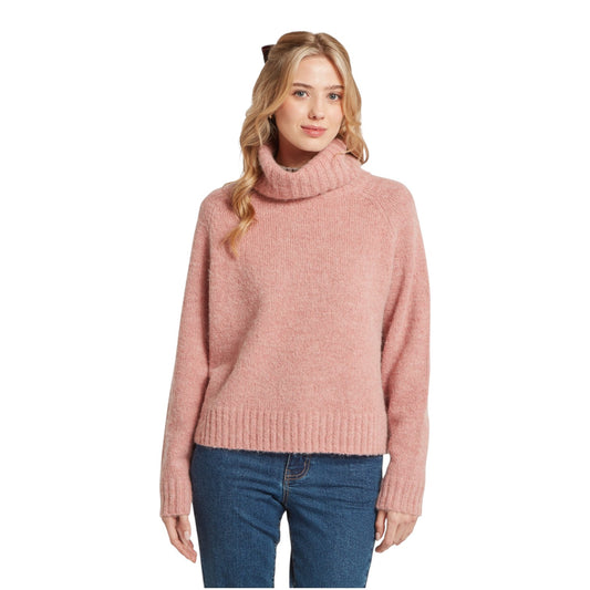 Woman wearing a pink turtleneck sweater and blue jeans on a white background