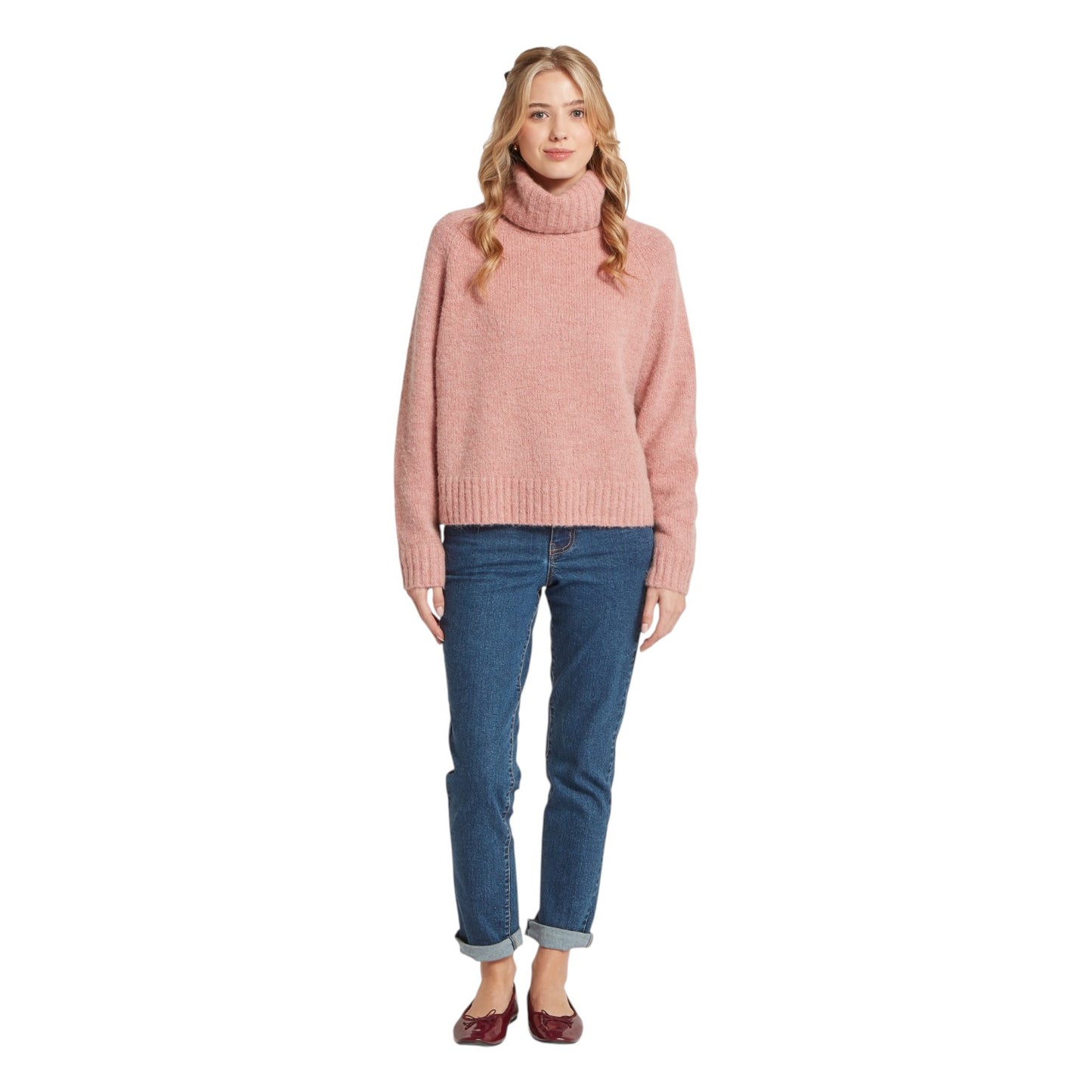 Woman wearing a pink sweater and blue jeans on a white background