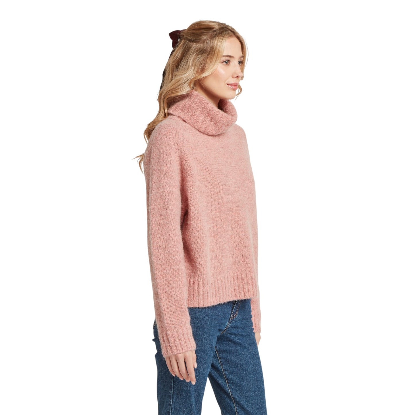 Woman wearing a pink sweater and blue jeans on a white background