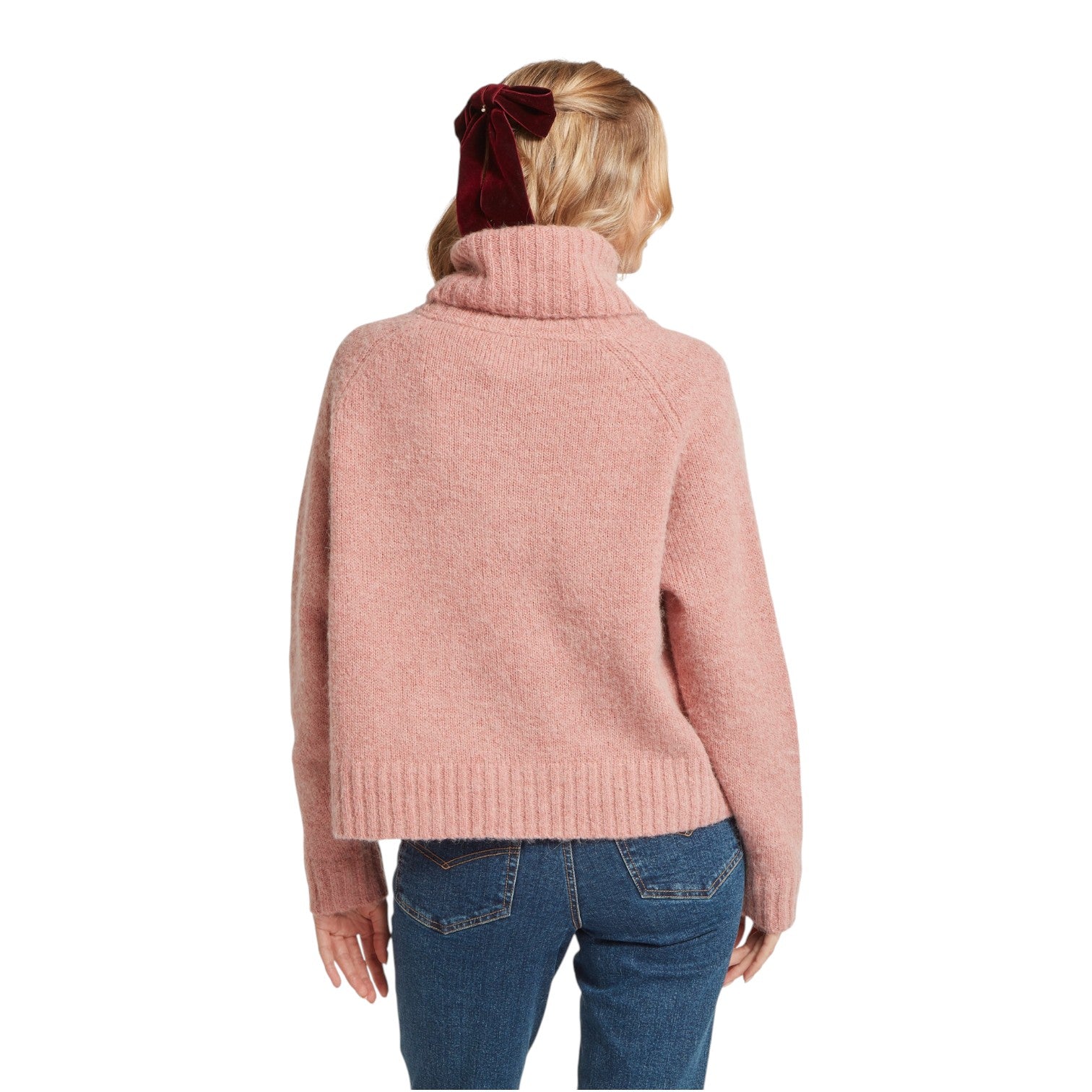 Person wearing a pink sweater and blue jeans on a white background