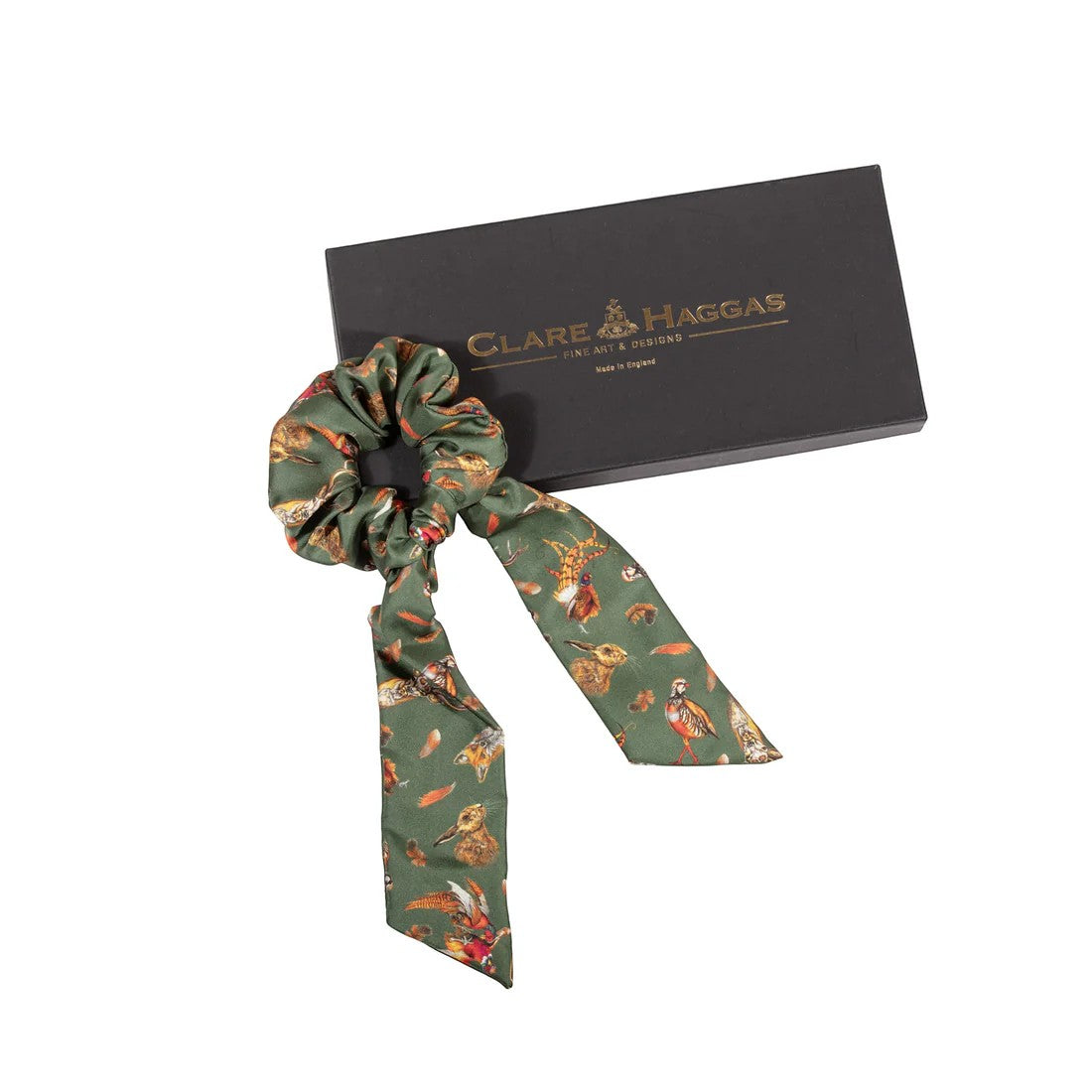 Green floral-patterned hair scrunchie with a black box featuring 'Clare Haggas' branding on a white background.